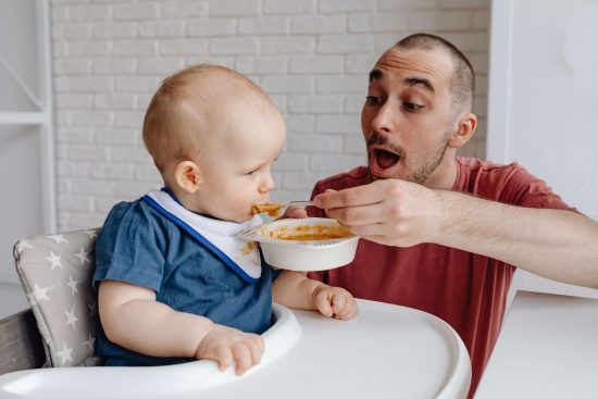 Beikoststart aufgeregter Papa füttert Baby